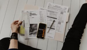 personne tenant du papier près d'un stylo et d'une calculatrice